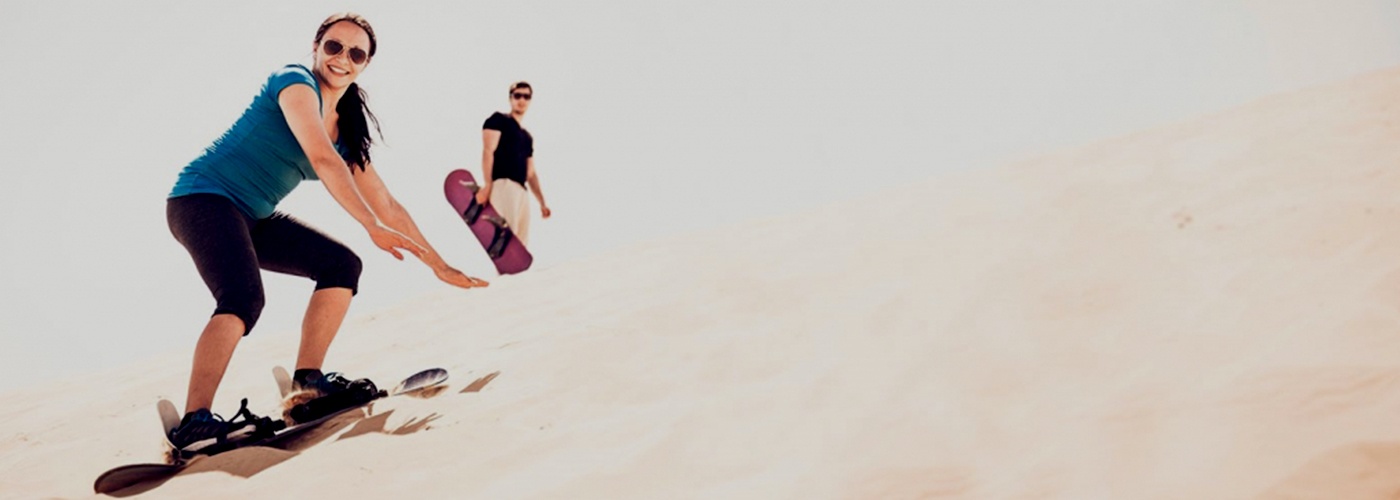 Leisure in UAE image banner of couple enjoying desert safari & sliding in UAE