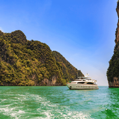 Private luxury yacht cruising the emerald waters and limestone cliffs of Phang Nga Bay, Thailand