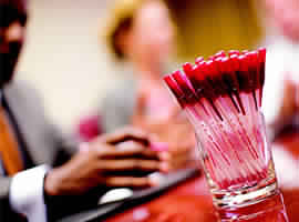 image of of red color pens in a glass kept & with business people busy in meeting