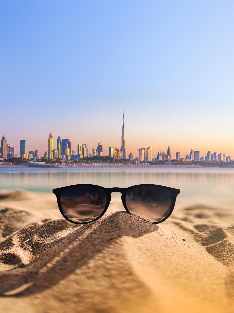 Banner image of Dubai buildings with burj Khalifa at the far with single sun glass at the sea shore