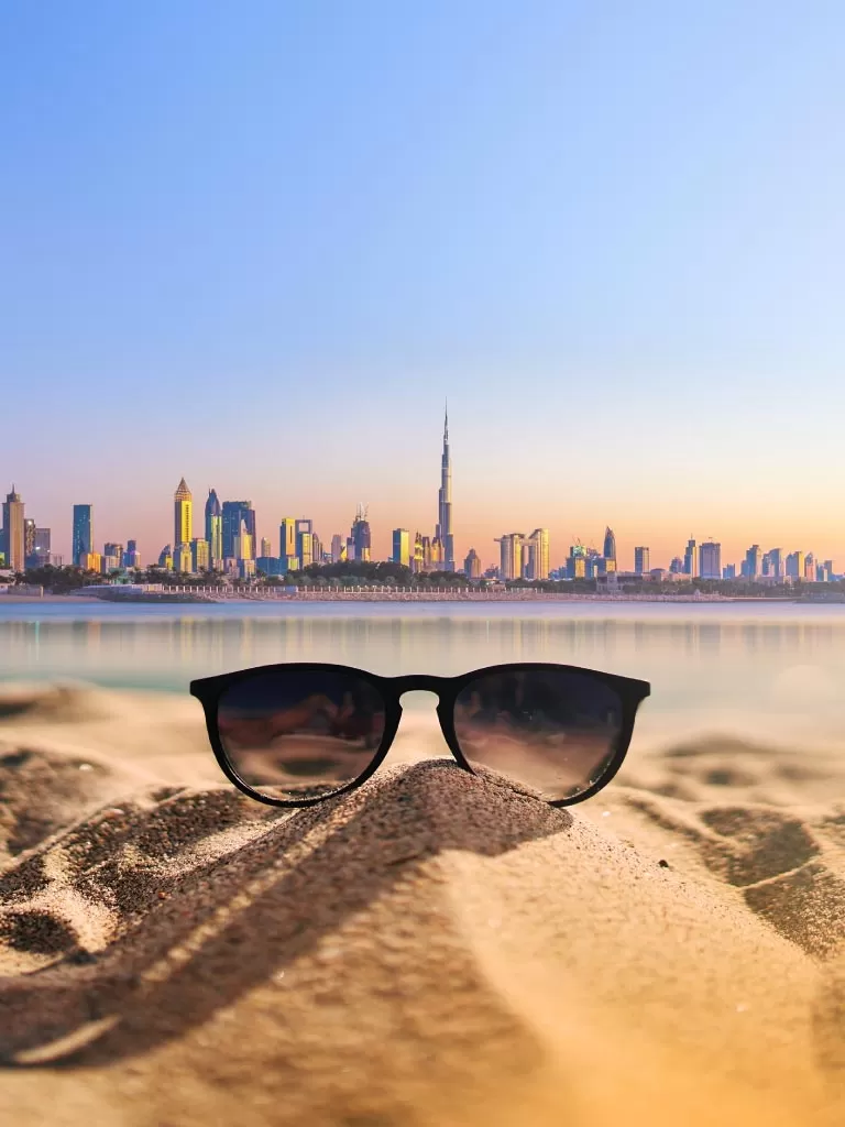 Banner image of Dubai buildings with burj Khalifa at the far with single sun glass at the sea shore